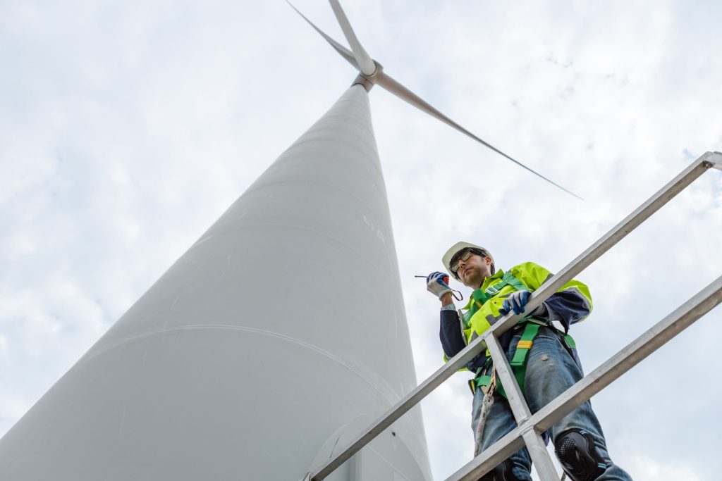 Wind turbine technicians holding walkie-talkie standing under a turbine station.